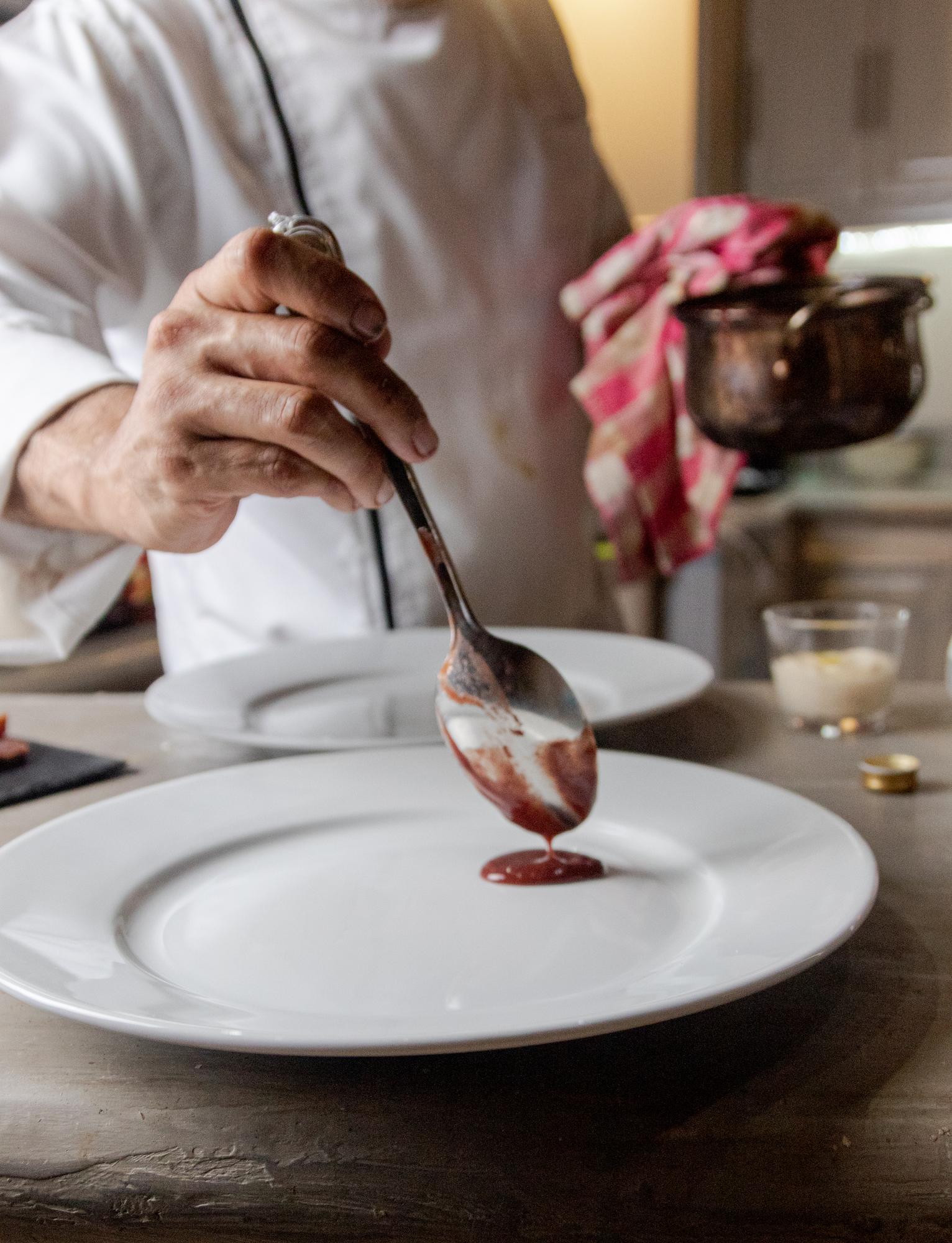 Chef preparing a plated dish on a warm pastel background